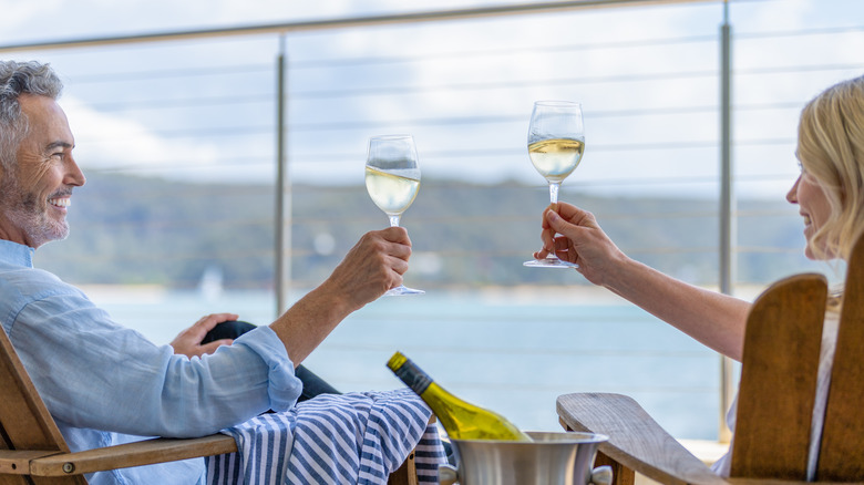 Man and woman cheers-ing with a glass of wine on a cruise ship