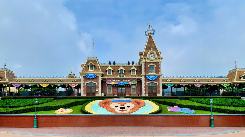 Exterior view of the Mickey Mouse Disneyland train station, and the gardens and flowers in front of the building, in Hong Kong Disneyland resort in Hong Kong