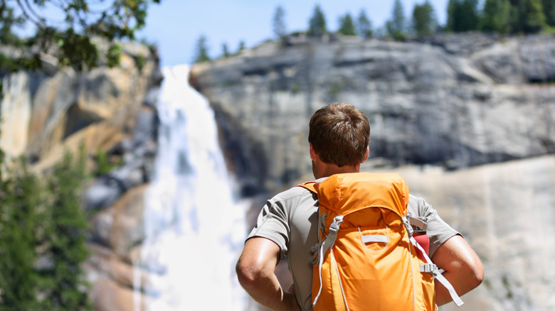 A Backpacker looking up at a waterfall in Yosemite National Park