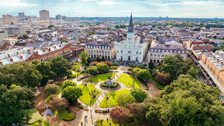 Aerial view of a park surrounded by buildings and a white cathedral in the French Quarter of New Orleans.