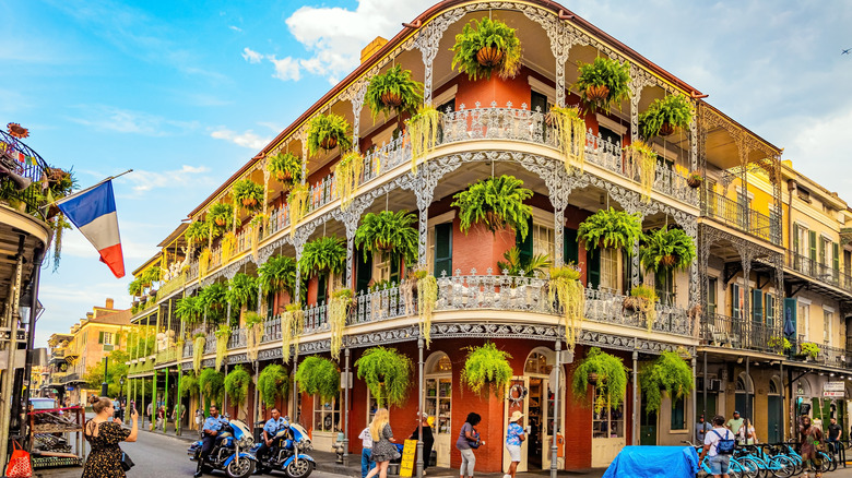 Three-story historic red brick building located in the French Quarter of New Orleans with lush hanging planters and wrought-iron balconies