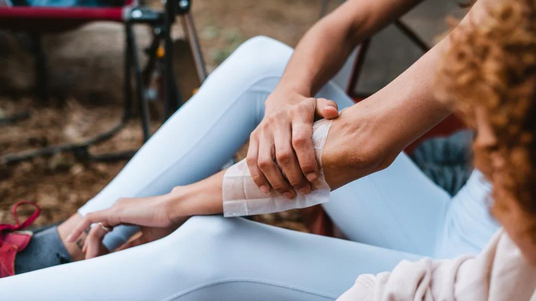 A camper wipes insect repellent onto her forearm using a towelette