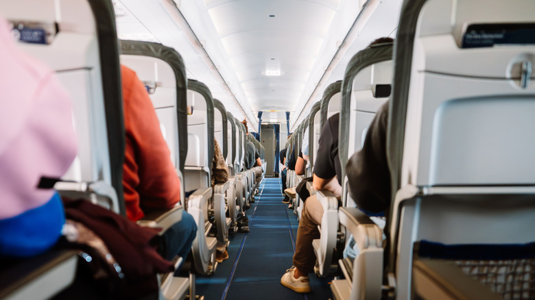 A plane cabin aisle, with full seats on both sides