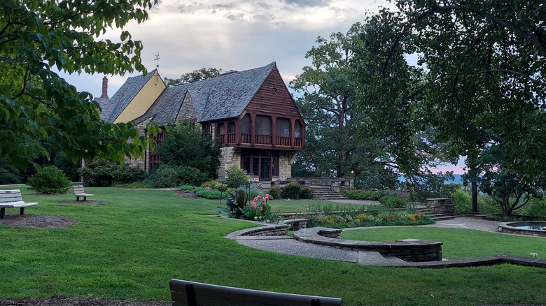 The Nims House in Bee Tre County Park next to a seating area full of chairs, ferns, and park trees.