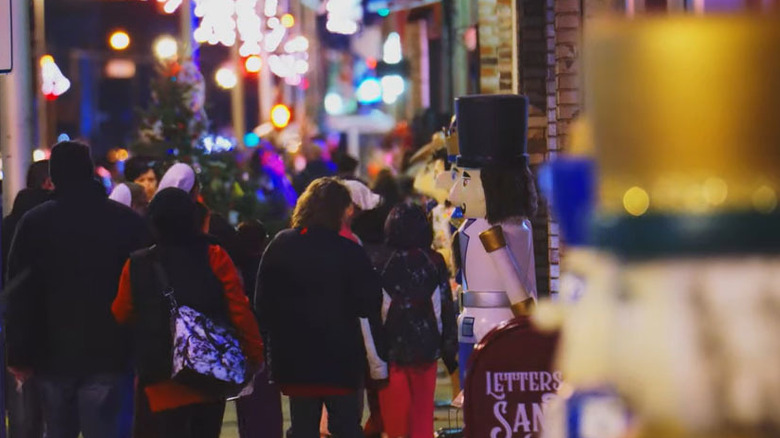 Crowds walking by life-sized nutcrakers along the street under holiday lights