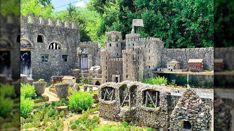 A castle and other sculptures made out of stones with plants around them.