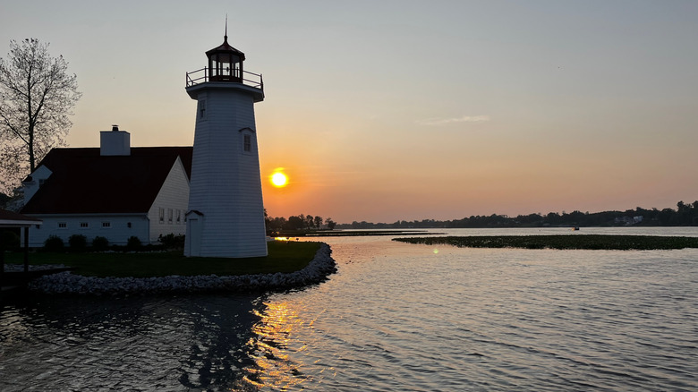 Lighthouse overlooking water with sunset behind it