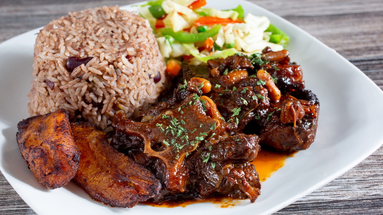 Braised oxtail with rice and greens on a white plate