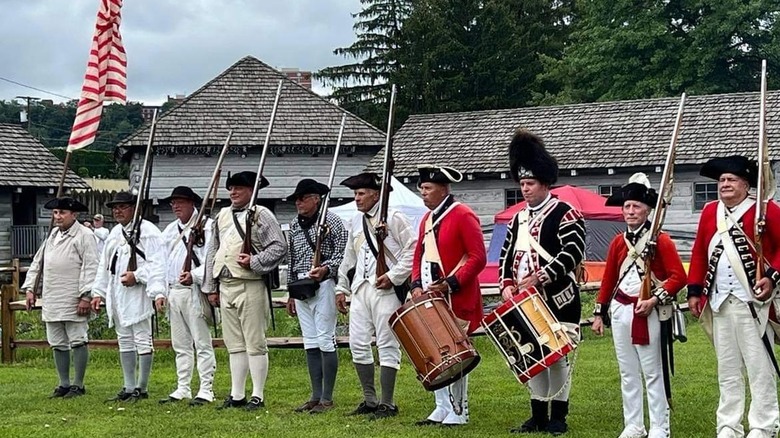 Ten reenactors dressed in 18th century attire in Historic Fort Steuben