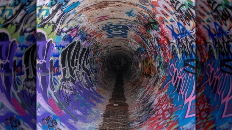 Tunnel with graffiti on wall and water on ground