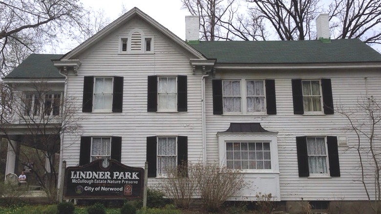 The exterior of a white estate house on cloudy day with a sign that says 