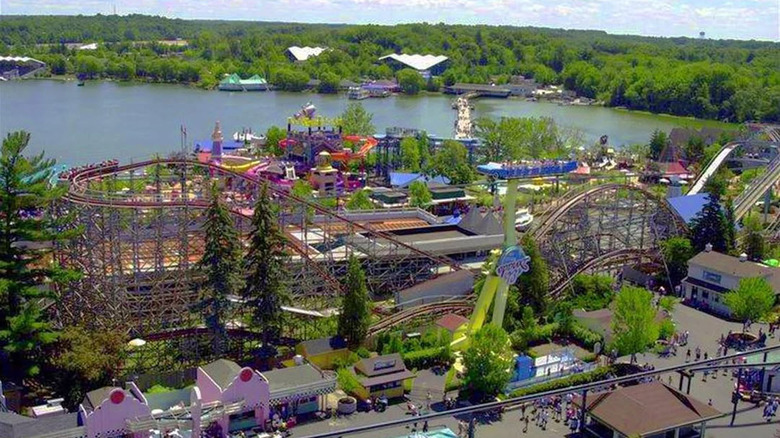 Aerial view of Giauga Lake before the park's closure, with a roller coaster in the foreground and a lake with a green treed shoreline behind it