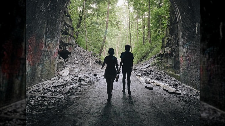 Woman and man silhouettes in Moonville Tunnel walking towards trees