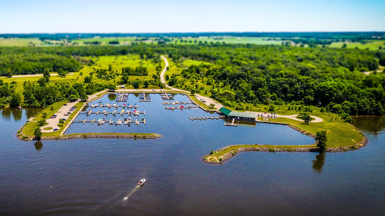 Marina at Buck Creek State Park, a lake with boats at docks and fields and trees in the background under a blue sky