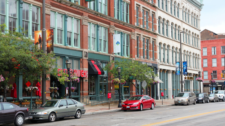 A tree and shop-lined street in front of stately building facades in Cleveland, Ohio
