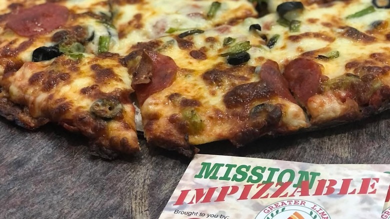 A pizza from a shop in Lima, Ohio with a Mission Impizzable brochure in the foreground