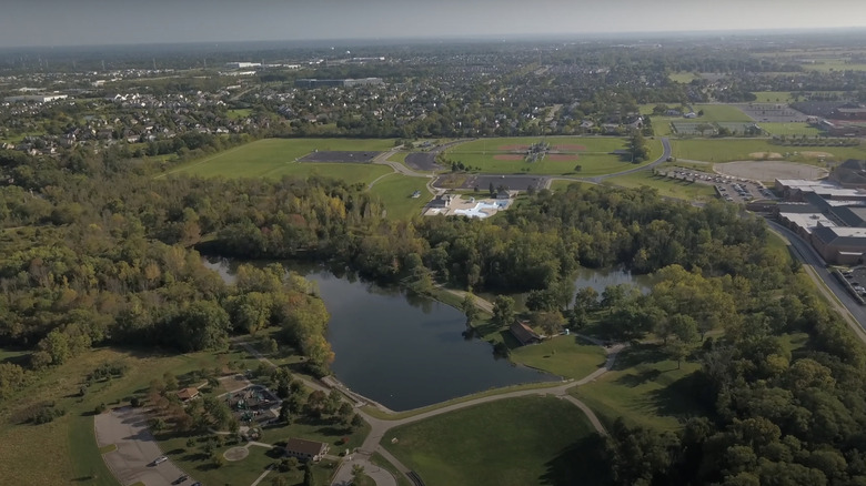 Aerial view of lake with green trees and a green field in Mason, Ohio