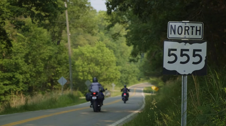Route 555 sign along a road with motorcyclists in Ohio
