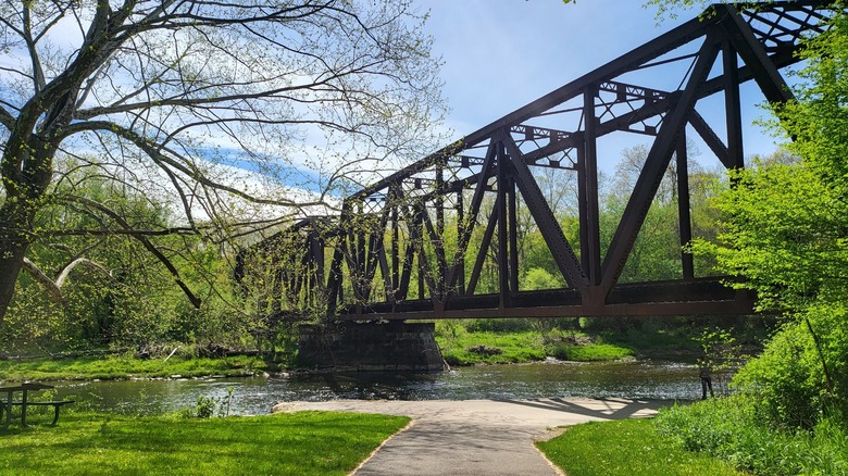 A steel bridge crosses the Allegheny River with a walking path in the foreground.