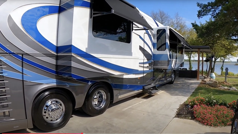 An RV with slideouts parked at an RV spot in a campground