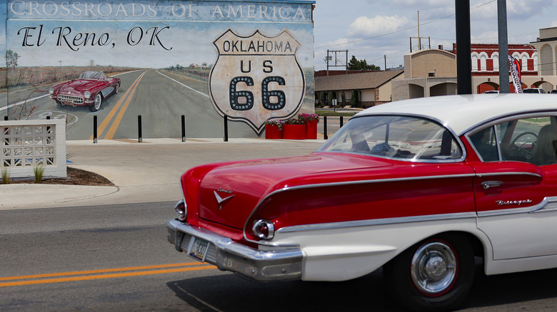 A classic car driving past El Reno's Route 66 mural