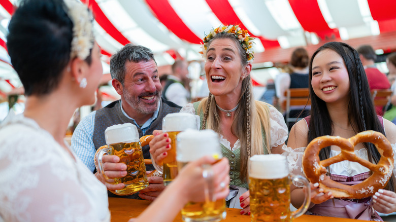 A group of friends at Oktoberfest tent with beer mugs sitting at a table