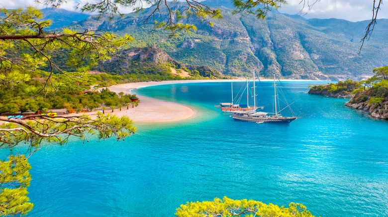Blue turquoise water and hills beyond, with two large sailboats off the shore of Oludeniz Beach in Turkey