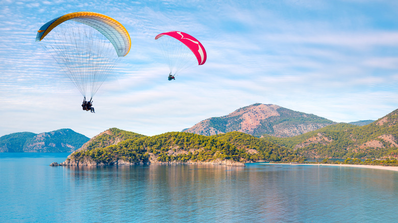 Paragliders in the air above water with mountains
