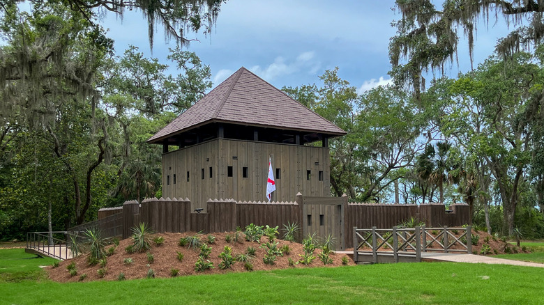 A fort surrounded by trees with flag hanging out front