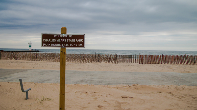 Charles Mears State Park's wide sandy beach along the coast of Lake Michigan, with a welcome sign in the foreground