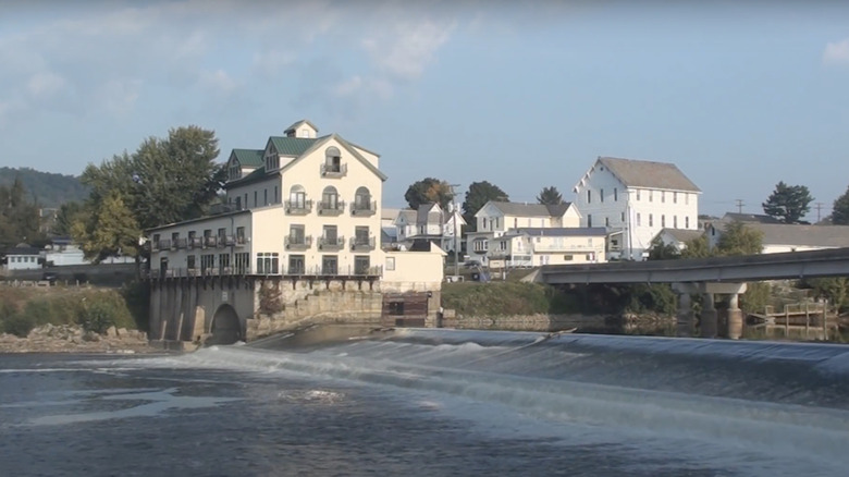 blue river under bridge with white building with windows in background under blue sunny sky
