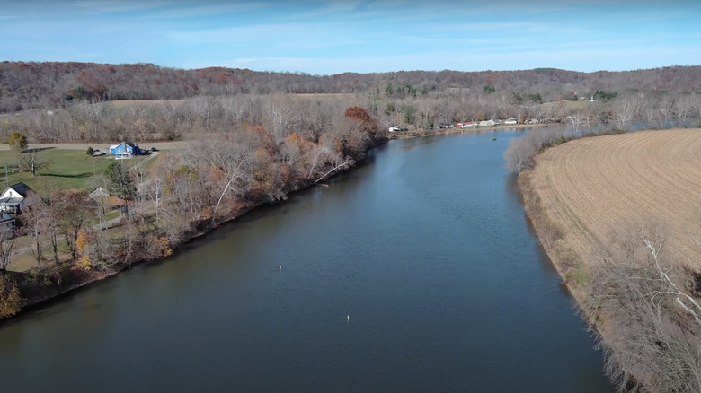 blue river with brown leaves and trees and farmland