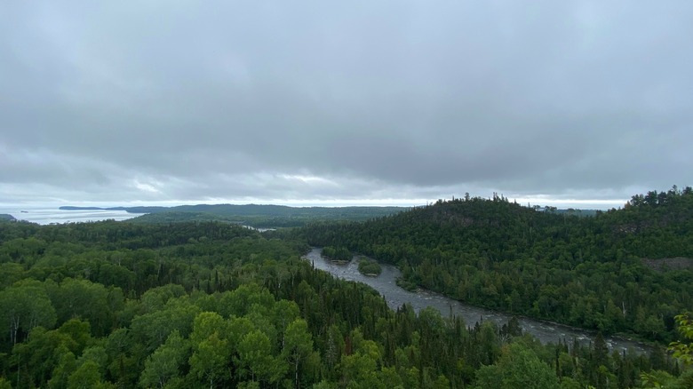 A sweeping view from an overlook with the river valley below, the lake in the distance, and forest all around