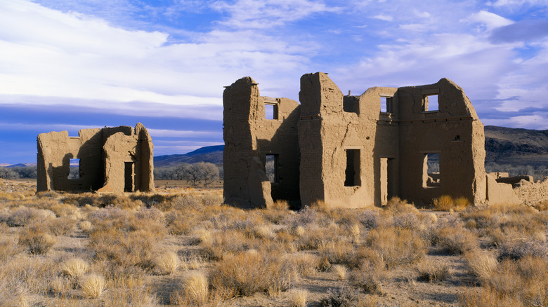 Ruins of Fort Churchill with sagebrush surrounding the dilapidated structures and blue sky overhead