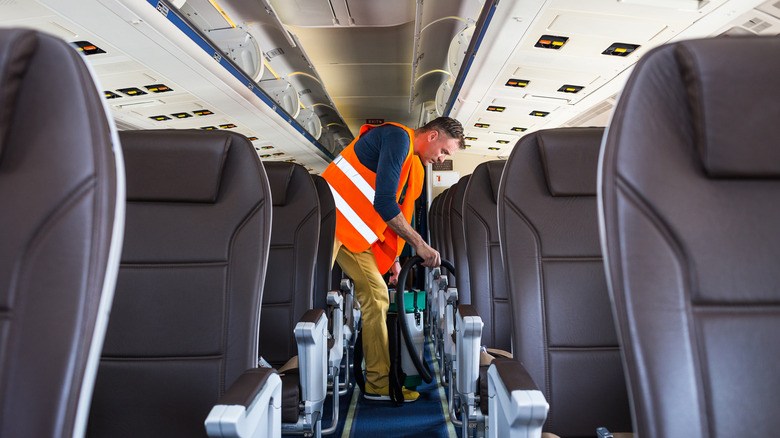 An airline staff member cleans an airplane before boarding