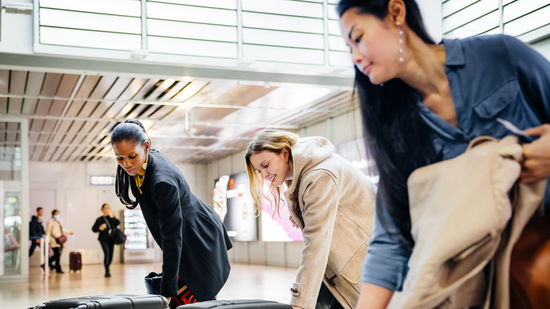 Women grabbing luggage off of an airport baggage carousel