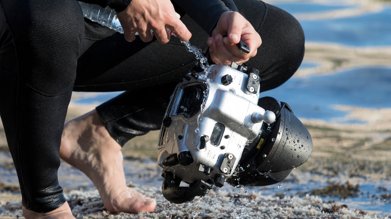 man rinses underwater camera with water