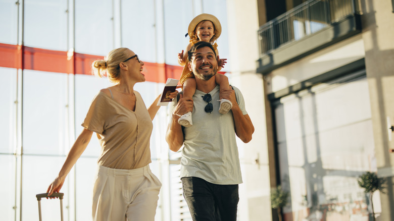 A family with a young child walking through a sunlit airport