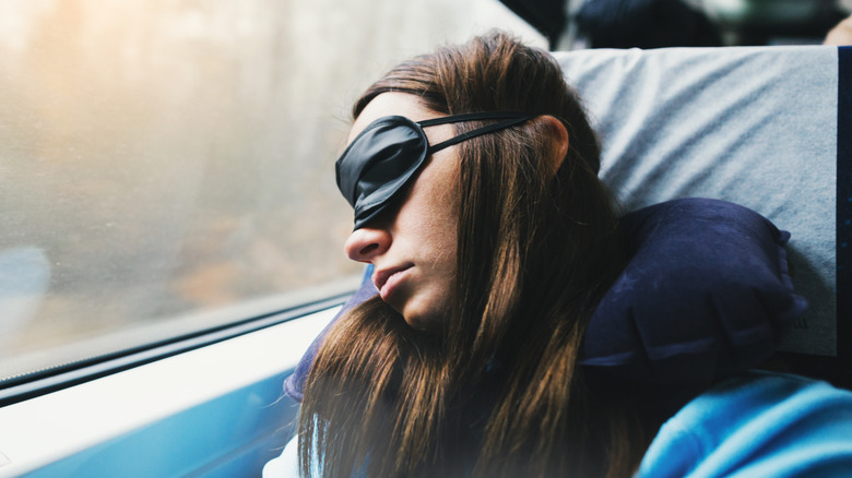 Woman sleeps soundly with eye mask and pillow on train