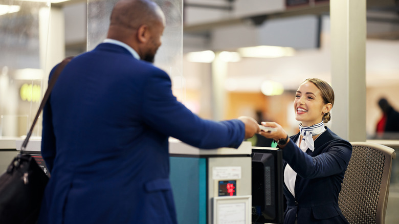 Airport staff handing over ticket at counter