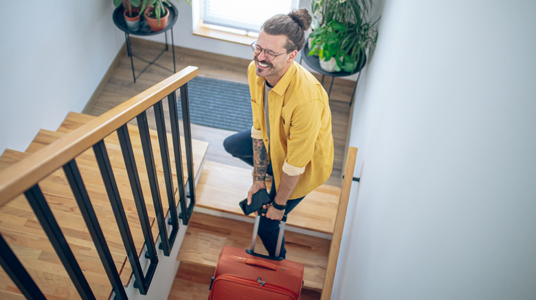 Young person hauling his heavy luggage up stairs