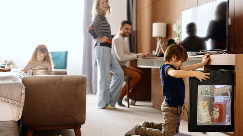 Boy opening refrigerator in a hotel room