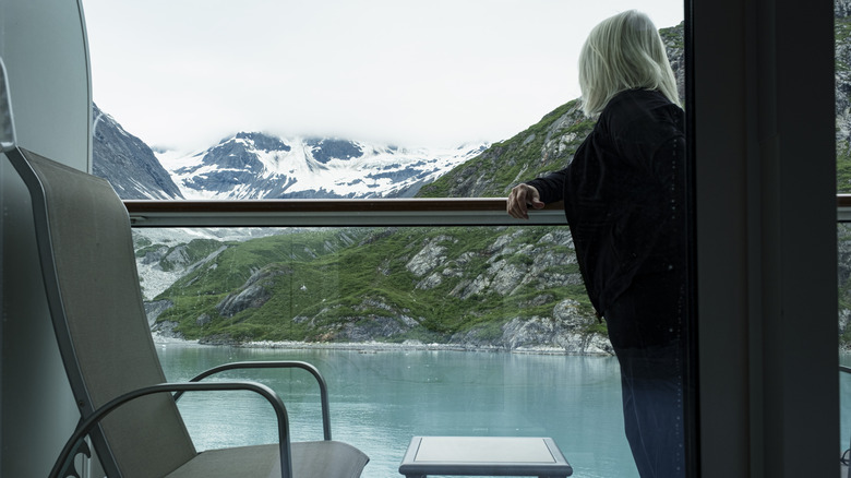 A woman looking out from her cruise balcony at Alaska's landscape