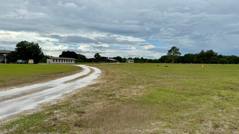 A chalky track curves through a field to a low-rise building and trees near Lake Panasoffkee, Florida