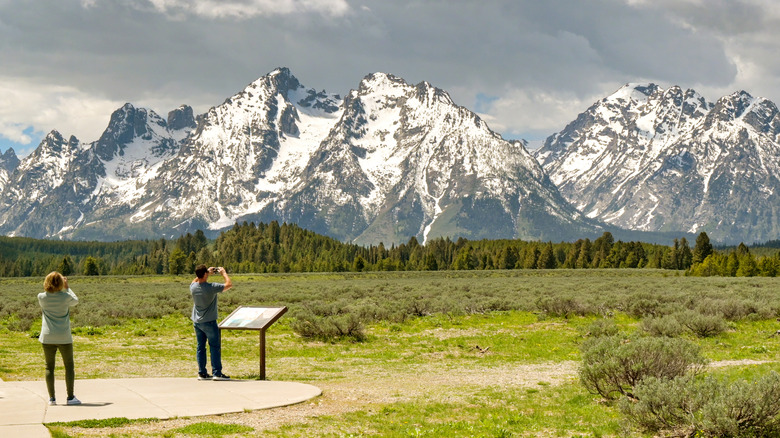 Tourists take photos of the snow-capped Grand Tetons