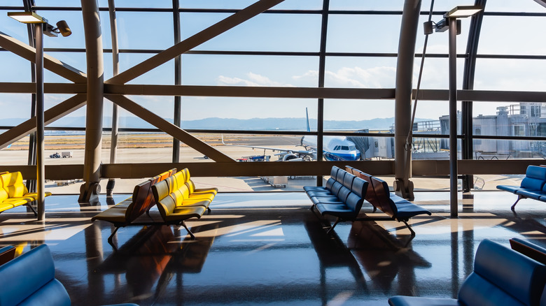 An airport with empty seats and a window with a plane at the tarmac