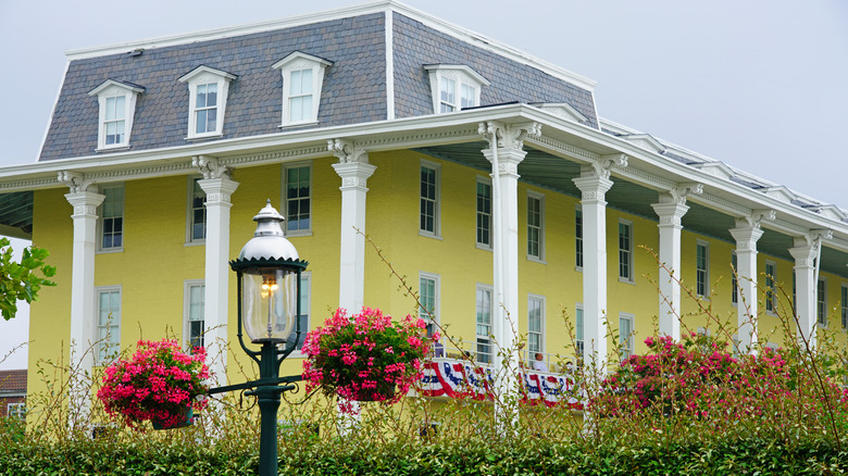 Congress Hall, yellow building with white pillars behind greenery and pink flowers