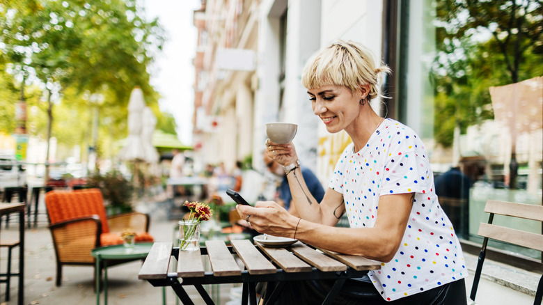 woman sitting outdoors while holding a coffee cup