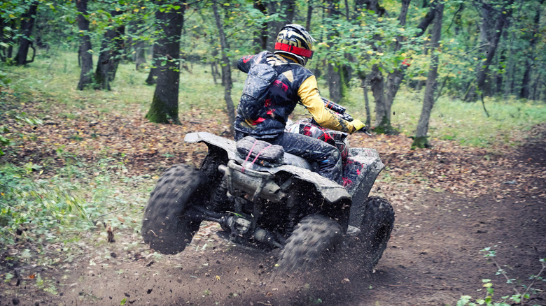 Man driving an ATV through a muddy forest