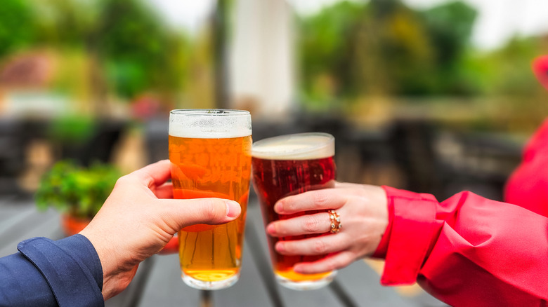 Two people cheering beer glasses in an outdoor setting